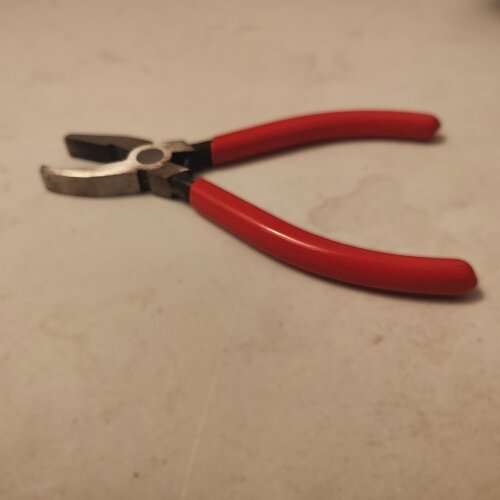 Breaker pliers gripping stained glass near a score line — used for nibbling tight curves in this stained glass cutting guide